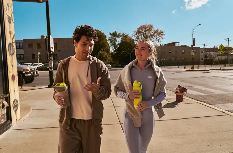 a male and a female walking and talking on the sidewalk