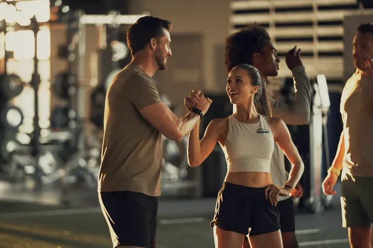 a male and female trainer shaking hands in the gym
