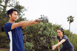 female trainer teaching client how to use kettlebells