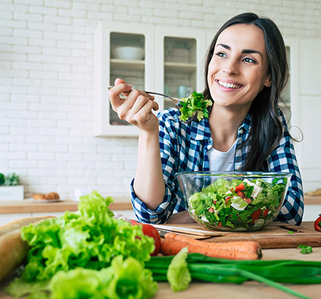 a woman eating a healthy salad to lower body fat