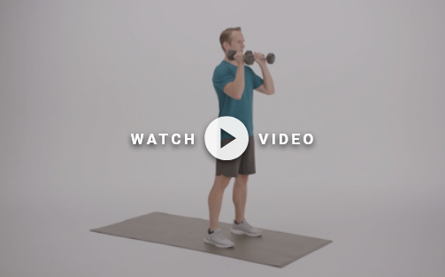 man standing with dumbbells at his shoulders