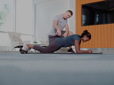 Trainer assisting client in kneeling plank mobile