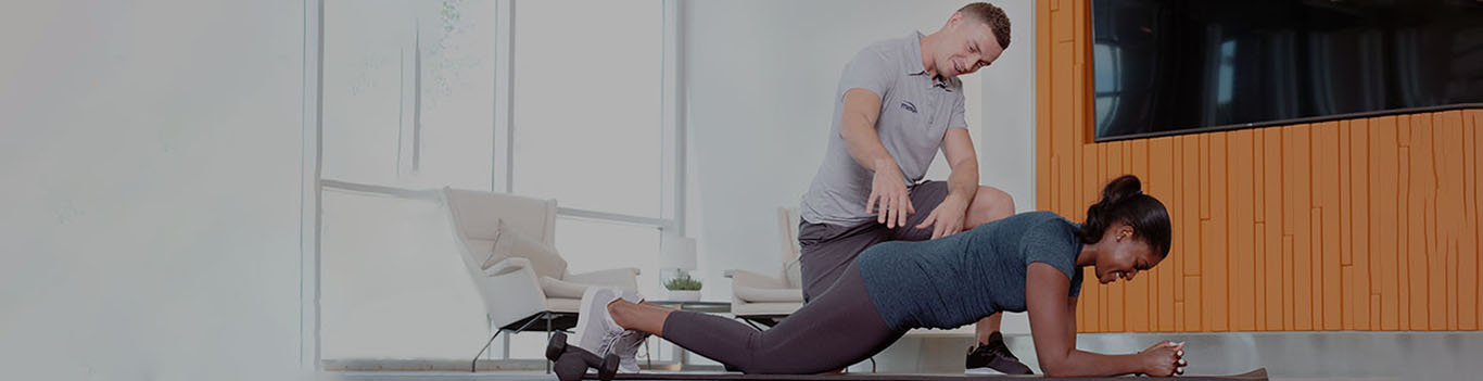 trainer assisting client in kneeling plank desktop