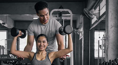 Trainer assisting client on seated over head press