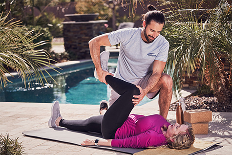 strech coach using massage gun on clients side