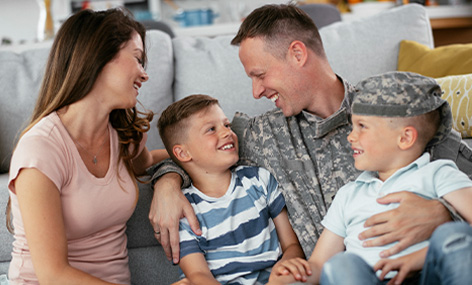 Military family of 4 smiling for photo in their living room