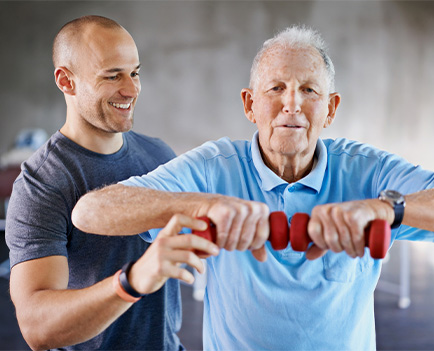 Trainer assisting elder man in gym