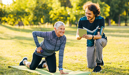 trainer assisting elder woman outside