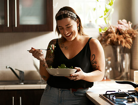 a woman eating a healthy salad after calculating her weight loss goals