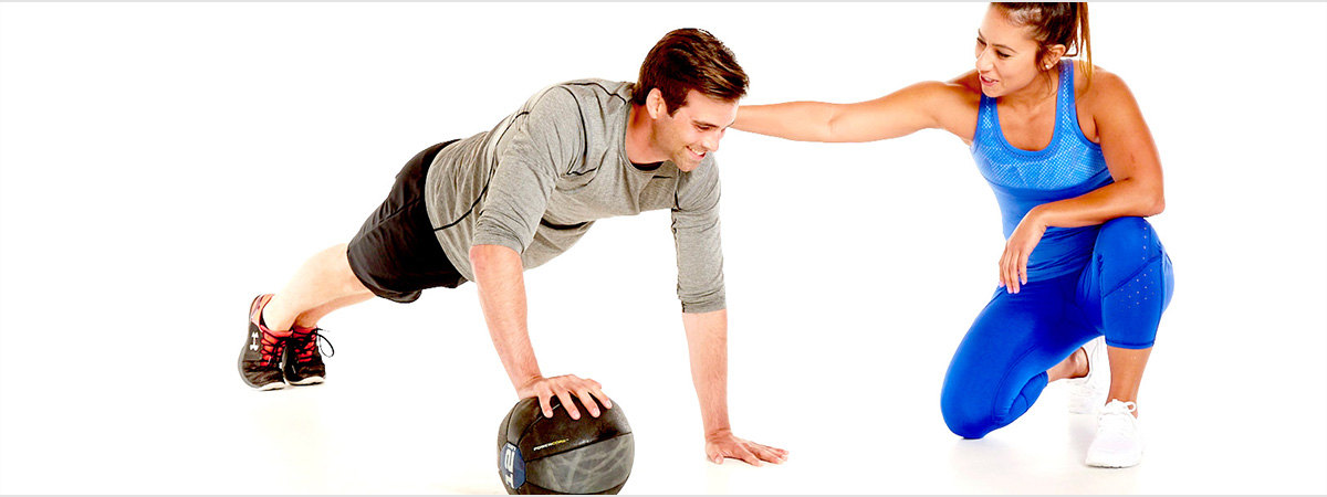 a master trainer showing a client how to do a medicine ball pushup