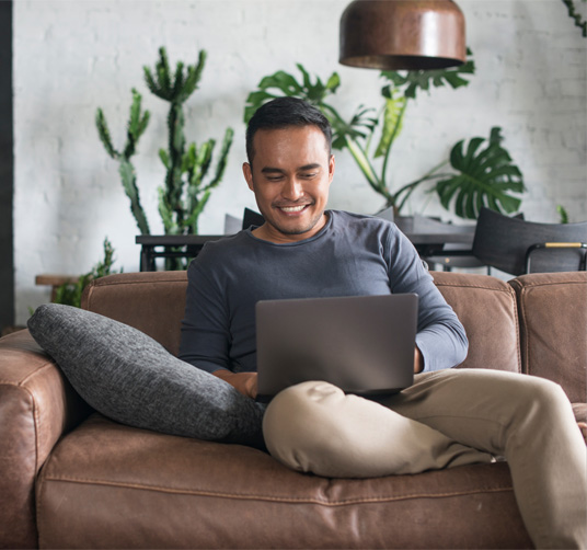 A man sitting on a couch with a laptop