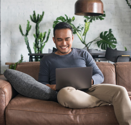 A man sitting on a couch with a laptop
