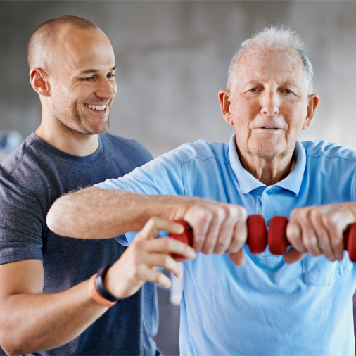 A male trainer helping a senior client
