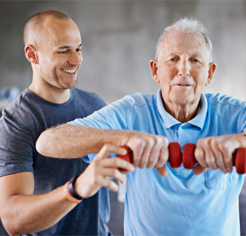 A male trainer helping a senior client