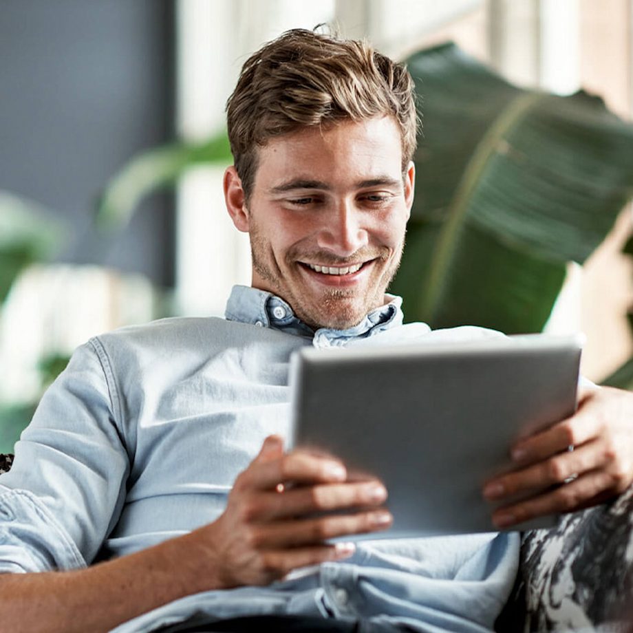 Male wearing button up holding tablet in hands