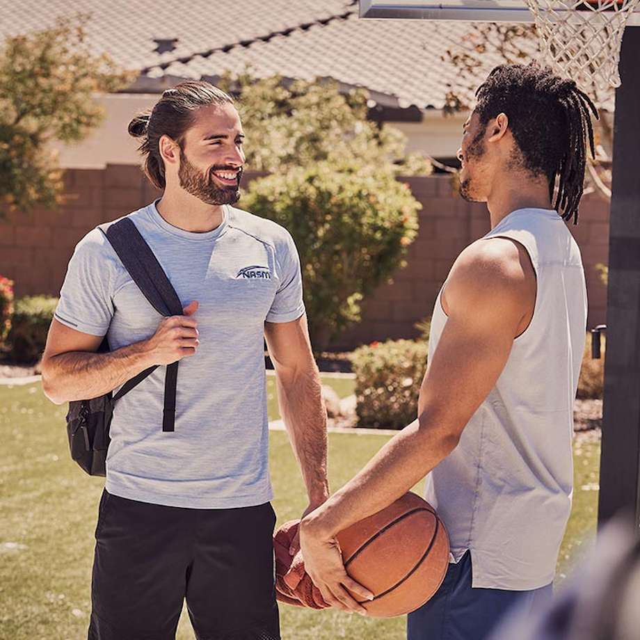 NASM Trainer talking to male client outside with basketball in hand