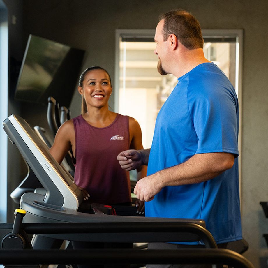 Female NASM trainer assisting male client on treadmill