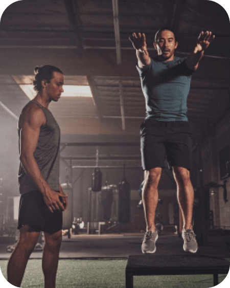 Male NASM trainer training male client on box jump inside gym