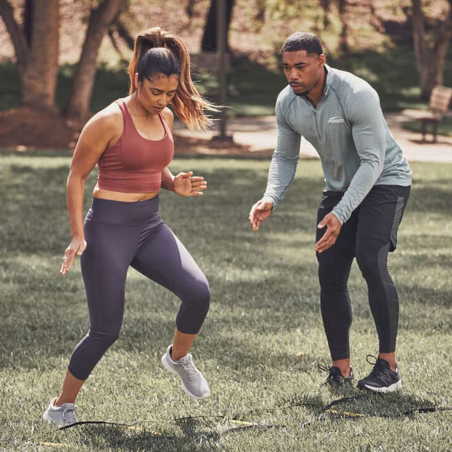 Male NASM trainer training female client outside with a foot workout drill