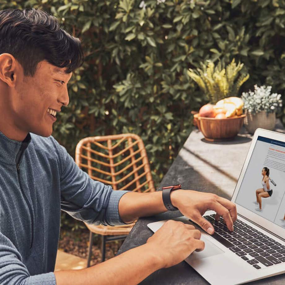 Male NASM student looking at the NASM online course on his laptop outside