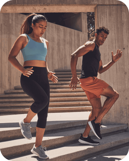 Female and male athletes running down cement stairs