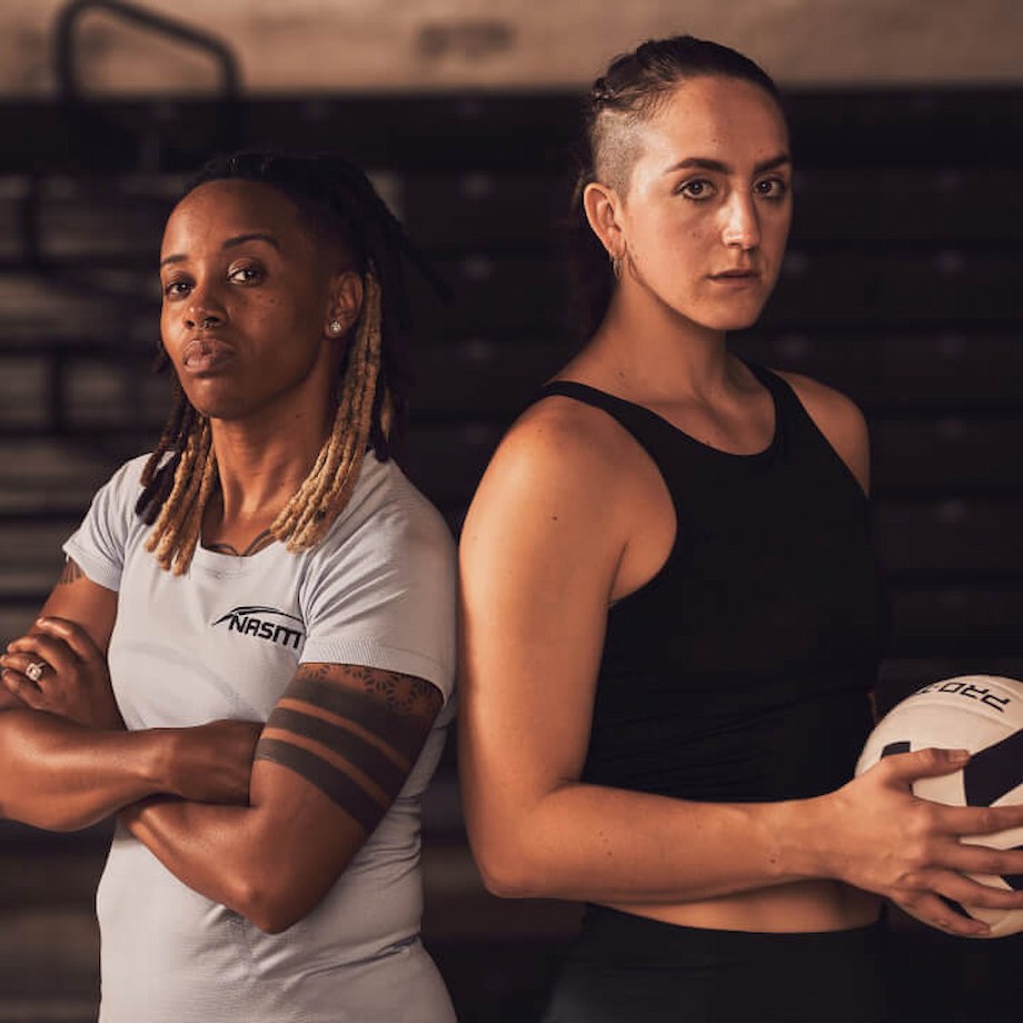 Female NASM trainer standing next to female athlete holding volleyball