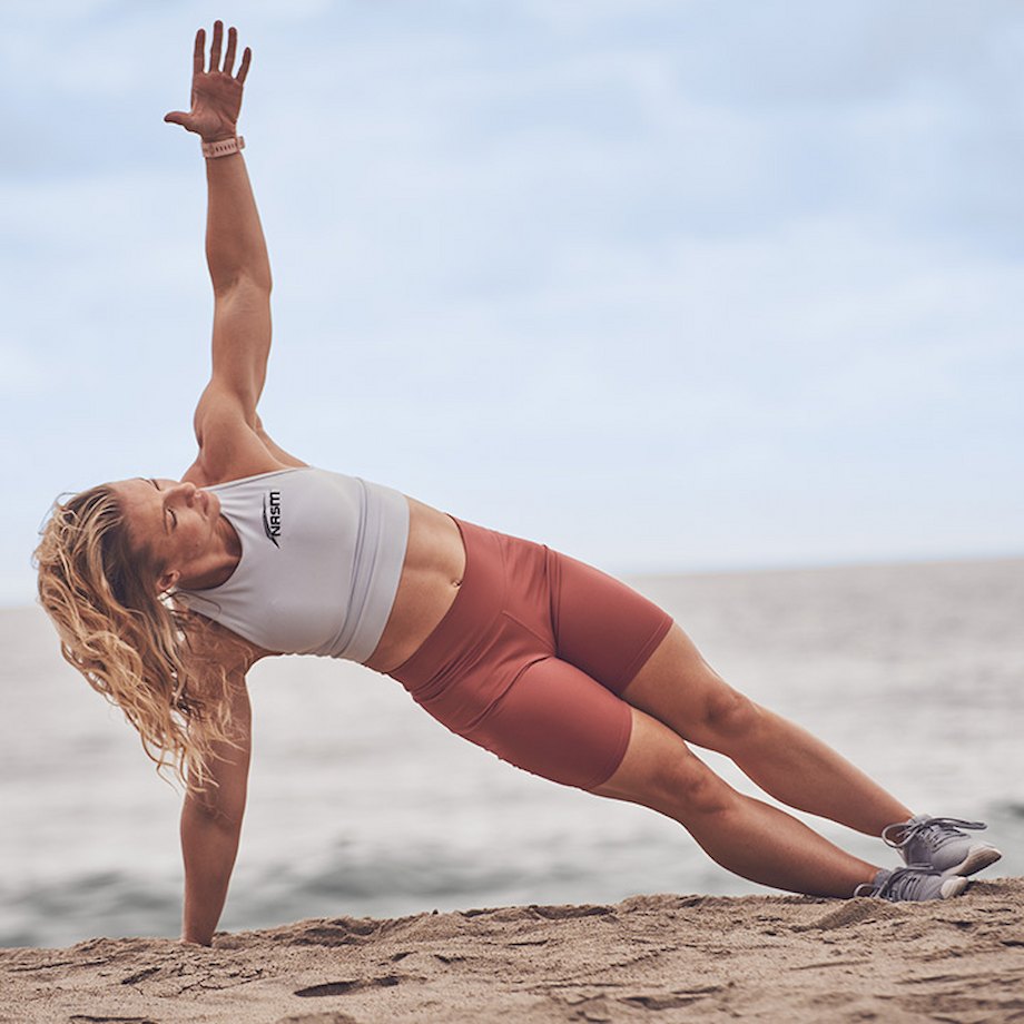 Female NASM trainer performing side plank on beach