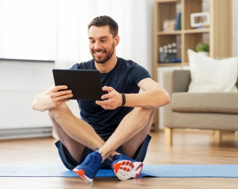 Man sitting on floor holding an Ipad smiling