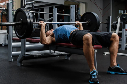 Male doing a flat bench press with 2 plates on each side