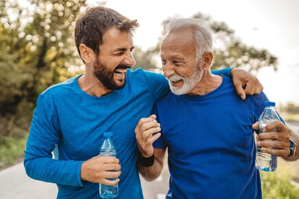 Younger male with arm over elder male walking outside