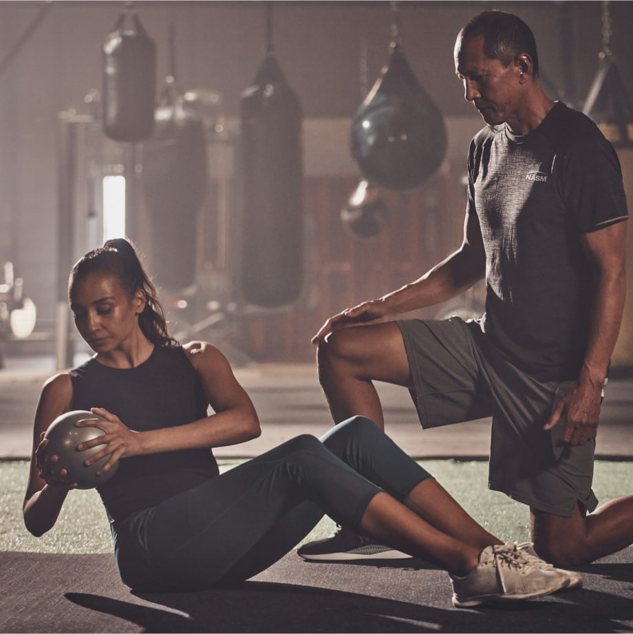 a male trainer helping a female client with a workout