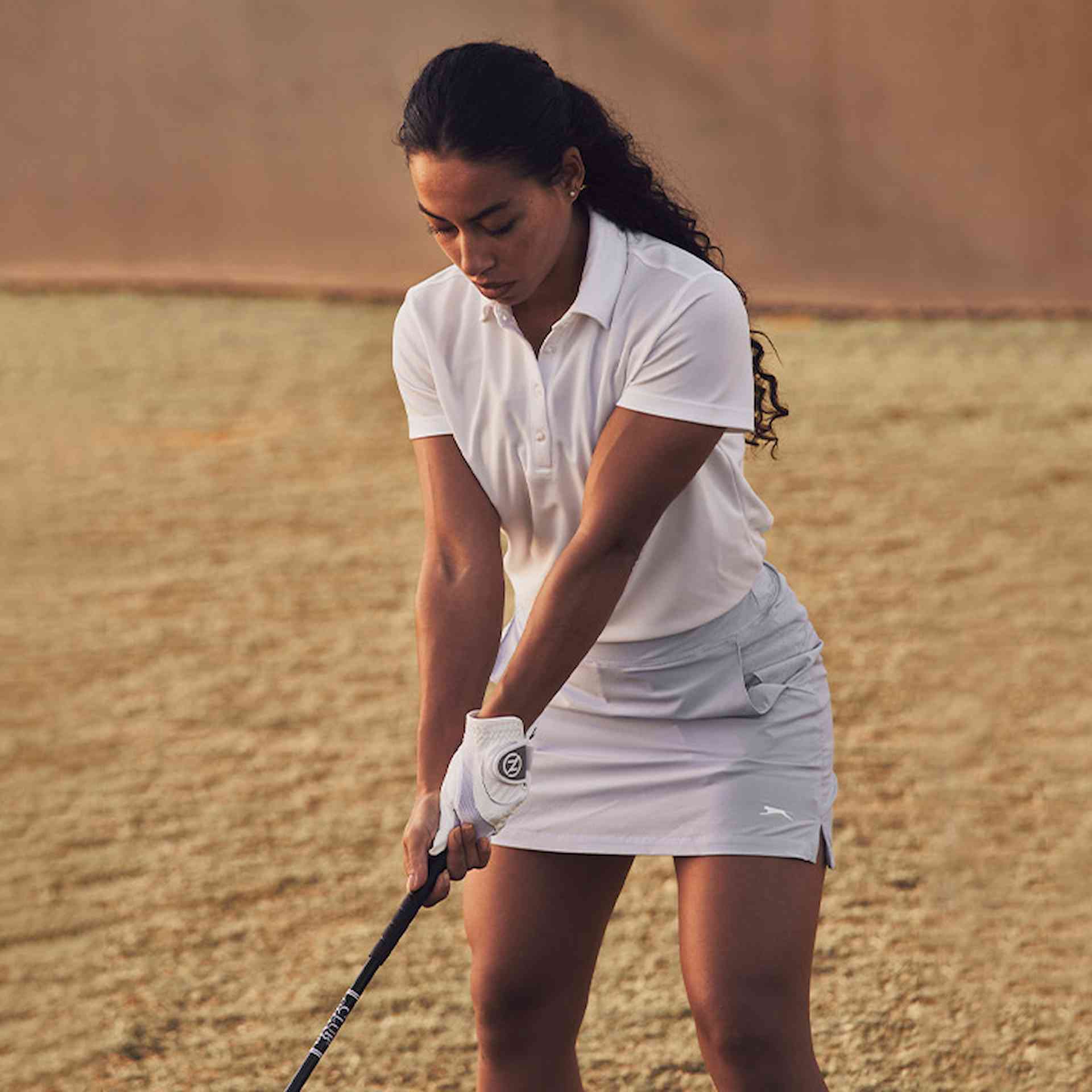 Female golf athlete swinging golf club outside