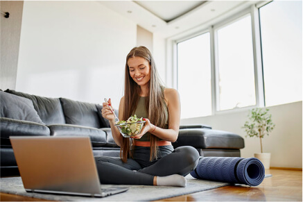 A lady sitting on in the living room eating a salad