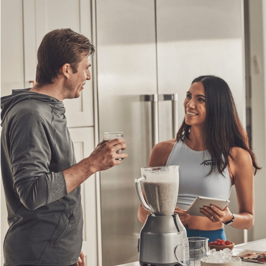 A female and male nutritionist making smoothies in a kitchen