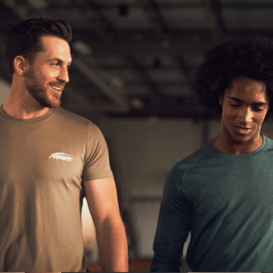 Male NASM trainer walking with male client inside gym