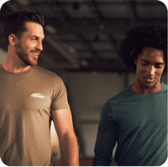 Male NASM trainer walking with male client inside gym