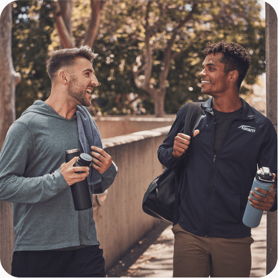 Male NASM trainer talking with male client outside holding water bottle