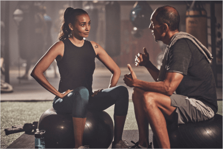 Male trainer talking with female client inside gym