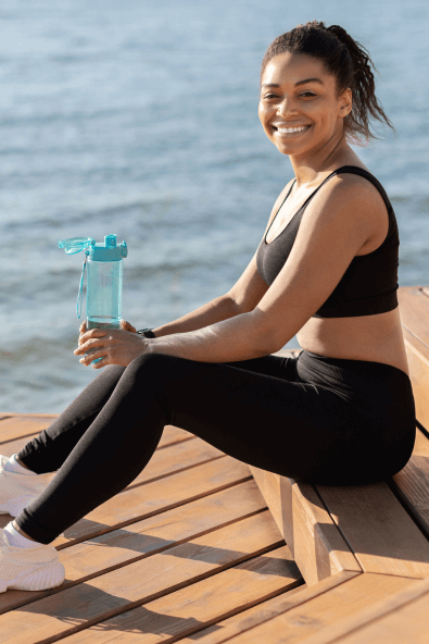 A woman in workout clothing sitting on a deck and smiling