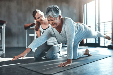 Female NASM trainer helping out an older woman exercise