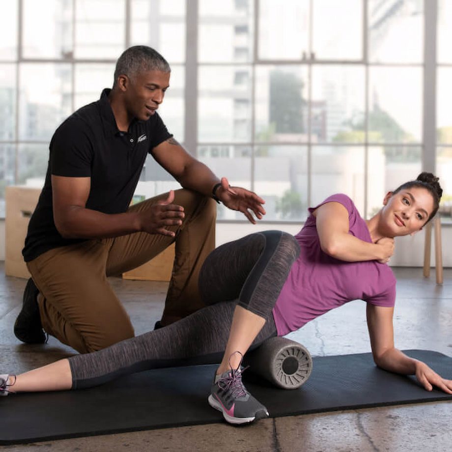 Prentiss assisting female client on foam roller size stretch