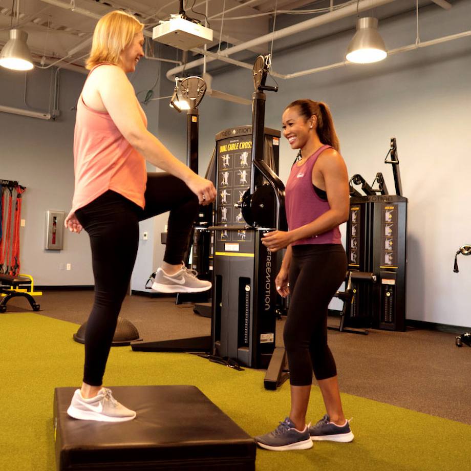 Female NASM trainer assisting female client in box exercise