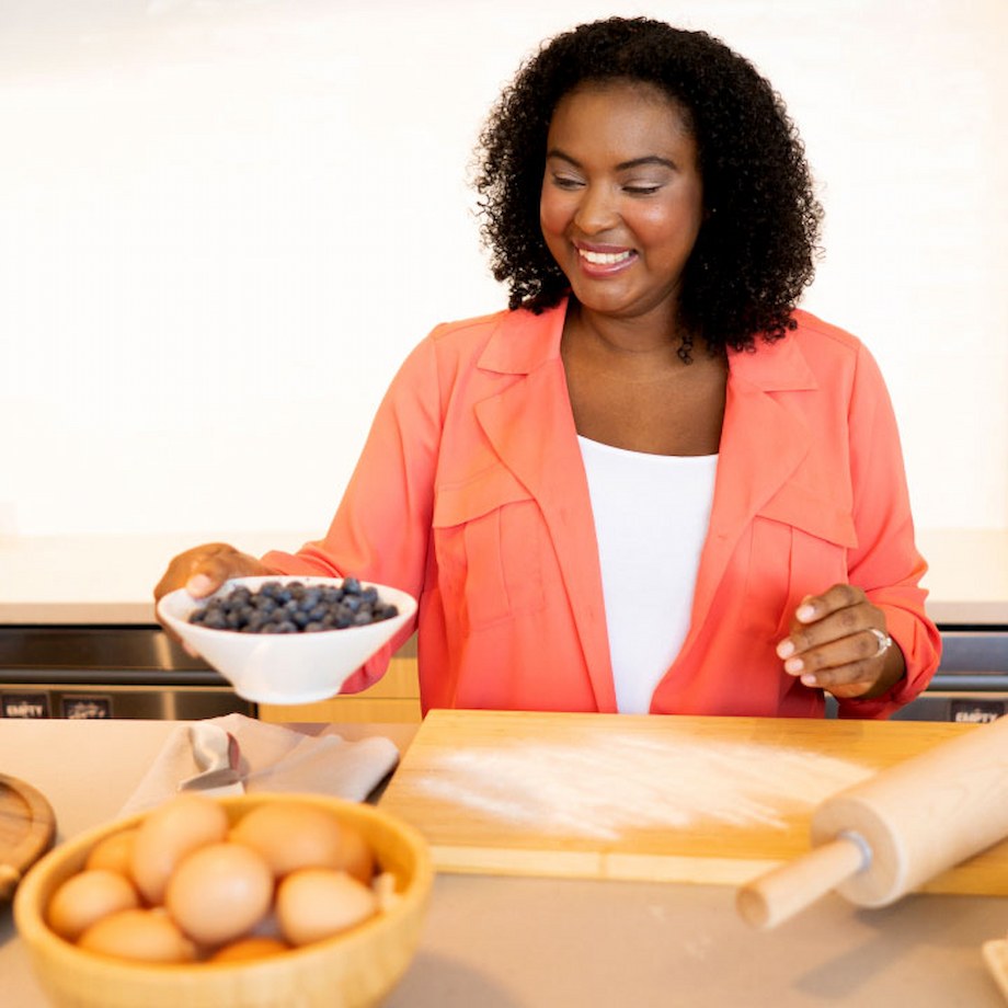 Female wearing pink long sleeve top holding bowl of blueberries