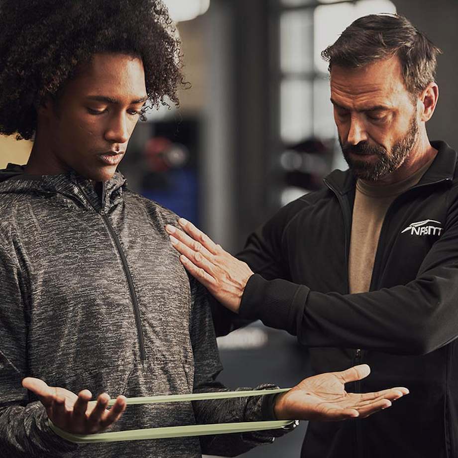 Male NASM trainer performing manual muscle testing on male client