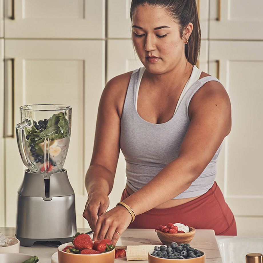 Female making healthy smoothie inside kitchen