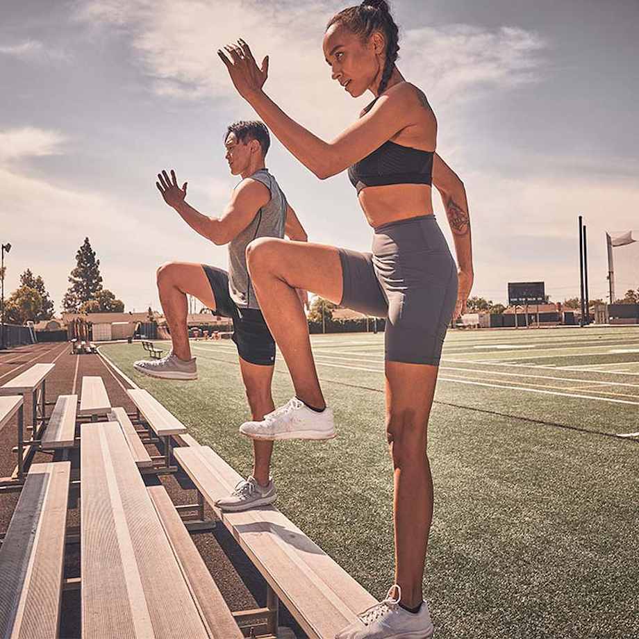 Female and male athlete doing step ups on bleachers outside