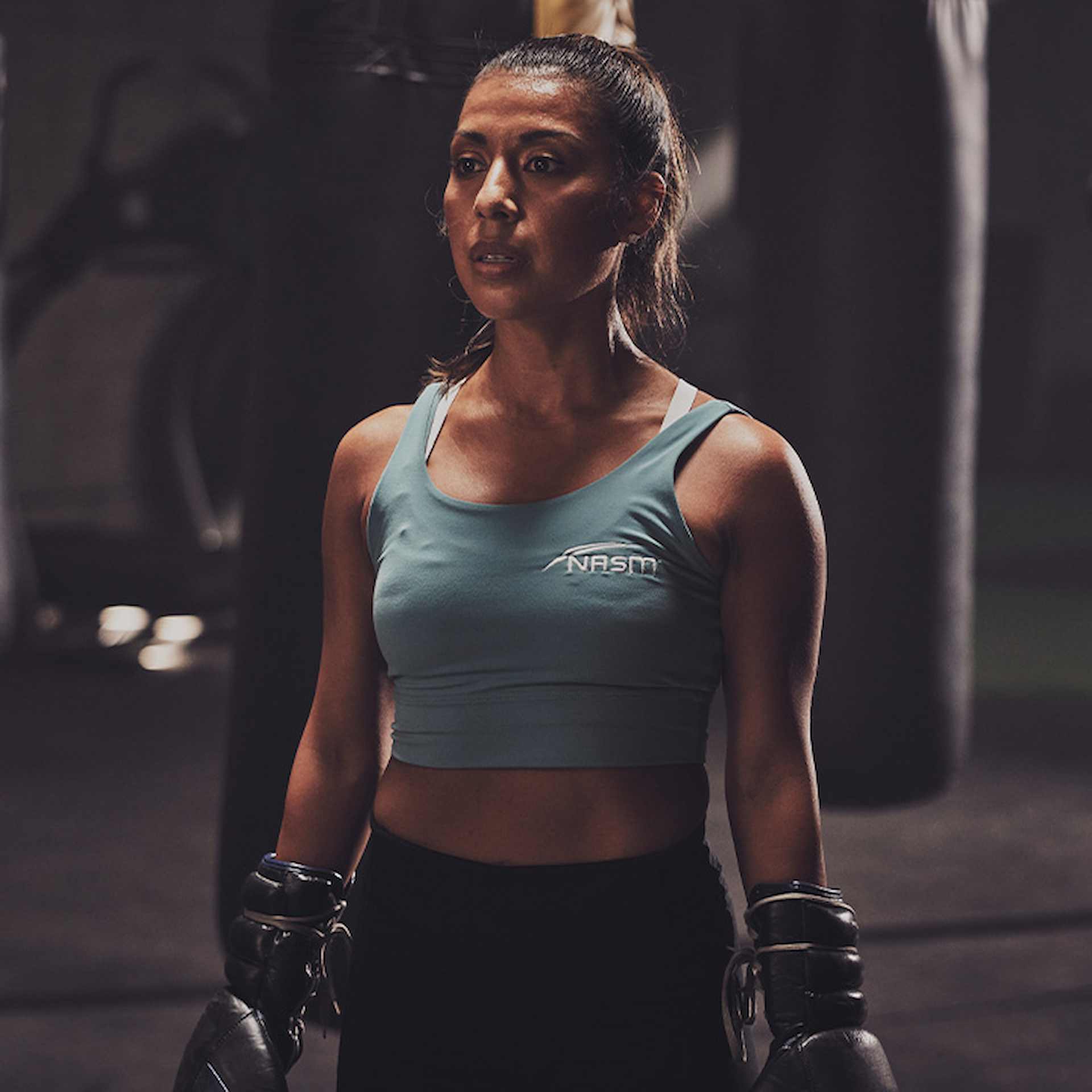 Female NASM trainer wearing boxing gloves wearing light blue NASM workout tank top