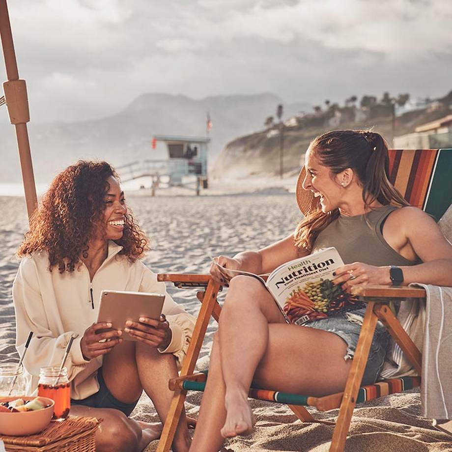 Two women sitting outside talking with a nutrition magazine in hand