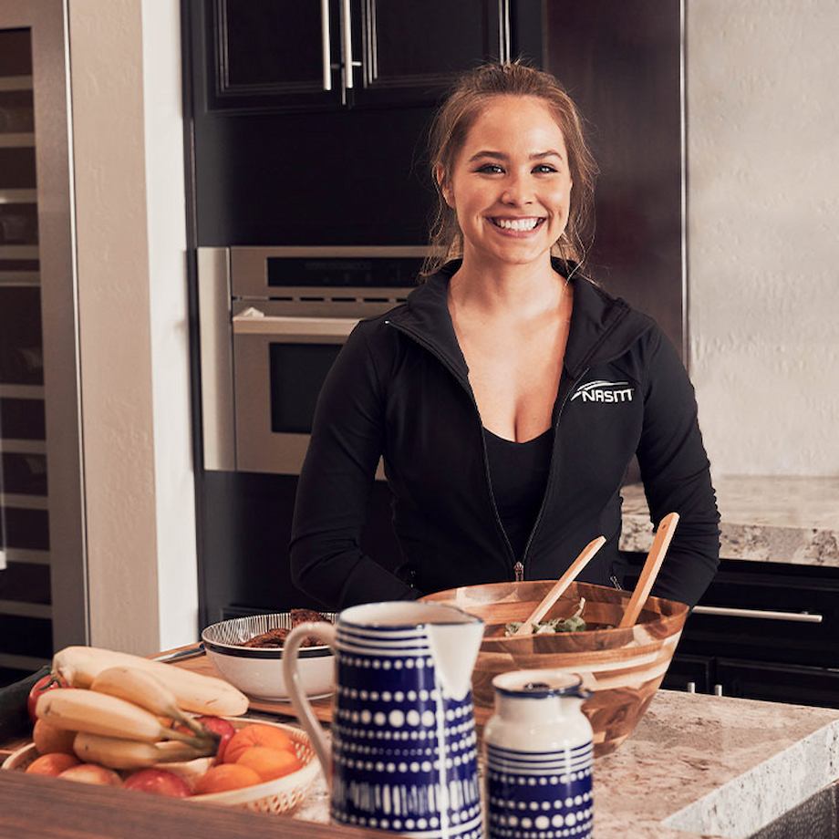 Female NASM Nutrition coach standing in kitchen with nutritional food