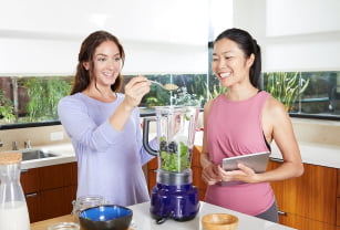 A Nutrition Coach and a smiling woman make a smoothie